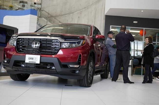 FILE - Customers confer with a salesperson as a 2022 Ridgeline pickup truck sits on the showroom floor of a Honda dealership, Friday, April 15, 2022, in Highlands Ranch, Colo.