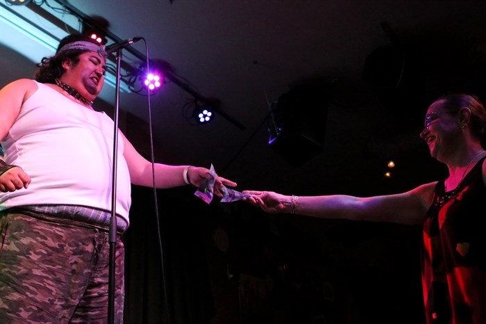 An audience member hands Rez Daddy money while he sings his own rendition of Post Malone’s “I Fall Apart” at Penticton’s Dream Cafe on syilx territory on June 4 during the kick off of the South Okanagan Similkameen Pride Society’s month-long Pride celebrations. Photo by A
