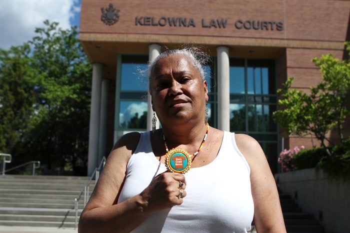 syilx Nation member Laurie Wilson holds up an “Every Child Matters” necklace outside of Kelowna Law Courts on June 22, 2022.