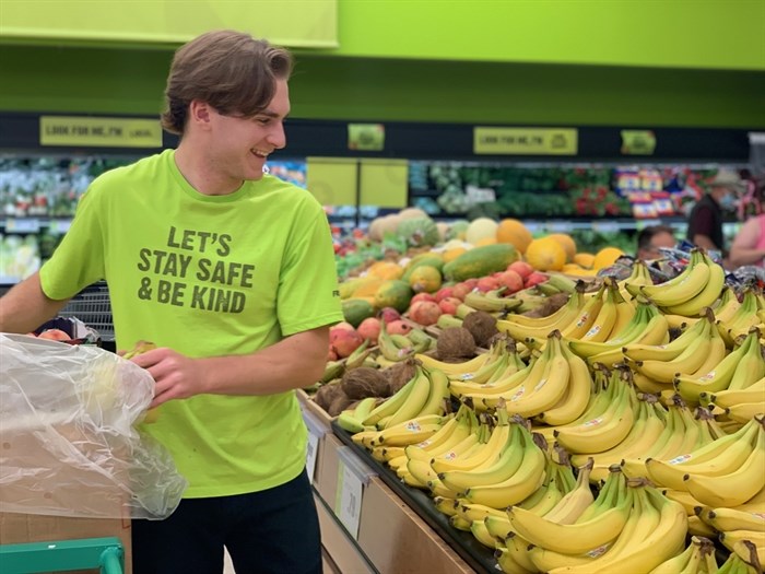 A Kelowna FreshCo employee stacks bananas