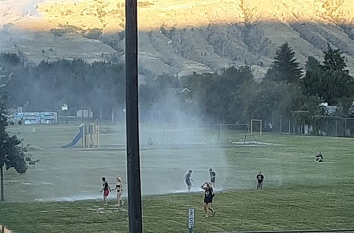 A fire crew in Westsyde, Kamloops cools neighbourhood kids off with sprinkler, July 27.