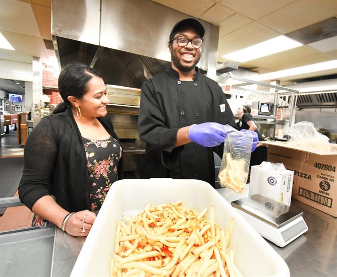 Joshua, a community living client and Boston Pizza employee, with restaurant manager Sony Grewal at work in the kitchen.
