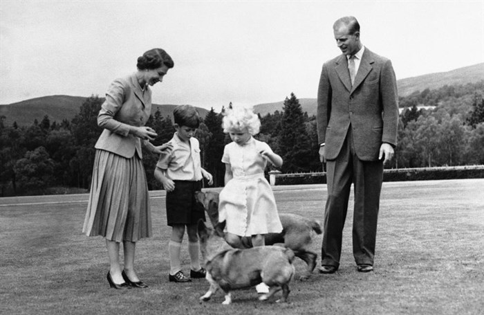 FILE - Queen Elizabeth II and the Duke of Edinburgh, with their children Prince Charles and Princess Anne, play with the Queen's corgi pet, 