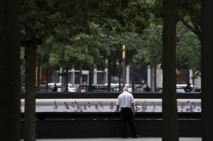 A man places his hand on name engravings during ceremonies to commemorate the 21st anniversary of the Sept. 11 terrorist attacks, Sunday, Sept. 11, 2022, at the National September 11 Memorial & Museum in New York.