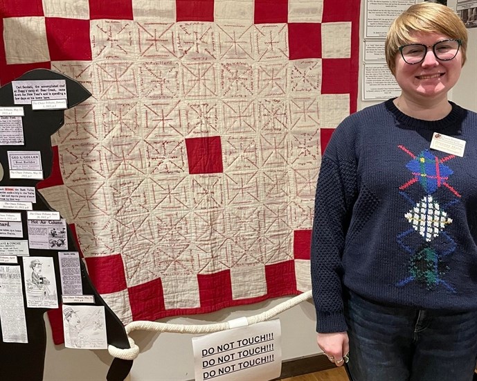 Chase and District Museum and Archives manager Breanne Malo stands beside a mysterious 100-year-old quilt on display.