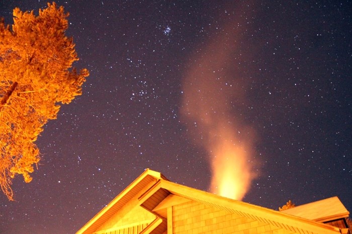 Smoke can be seen coming out of a chimney on a cold night.