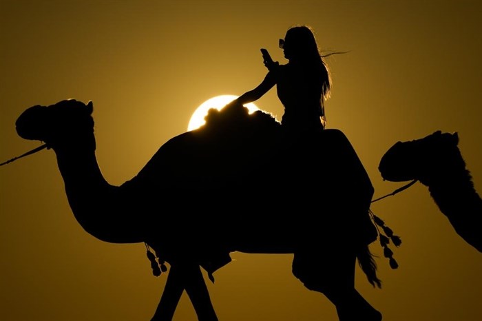 A woman looks at her photo while riding a camel in Mesaieed, Qatar, Nov. 26, 2022.