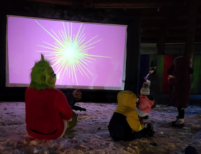 The Grinch watching The Grinch Who Stole Christmas with a small fan. 