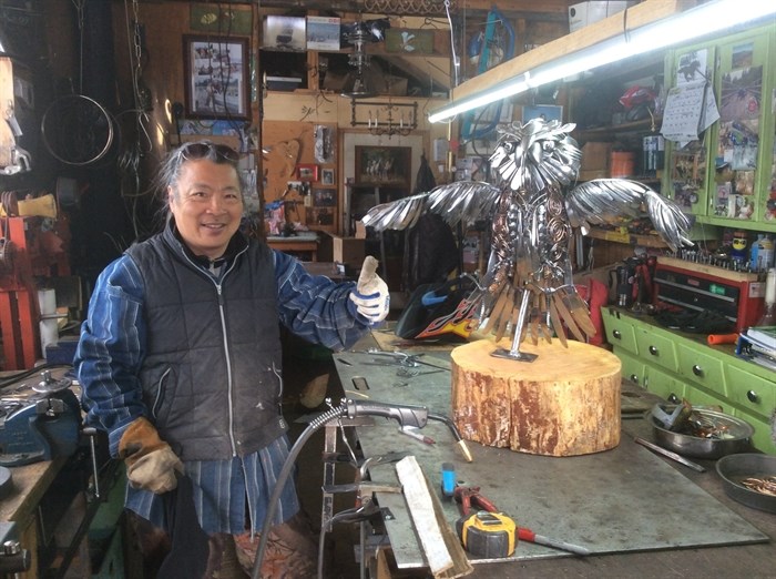 Osprey Lake metal artist Mark Wong with owl sculpture. 