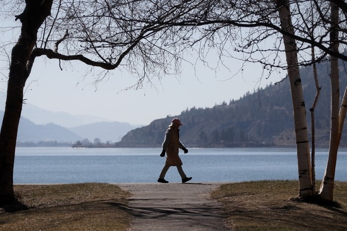 A person walks near the shore of cnx?lkip (Sun-Oka Beach Park) by k?úsx?nítk? (Okanagan Lake) on March 22, 2023.