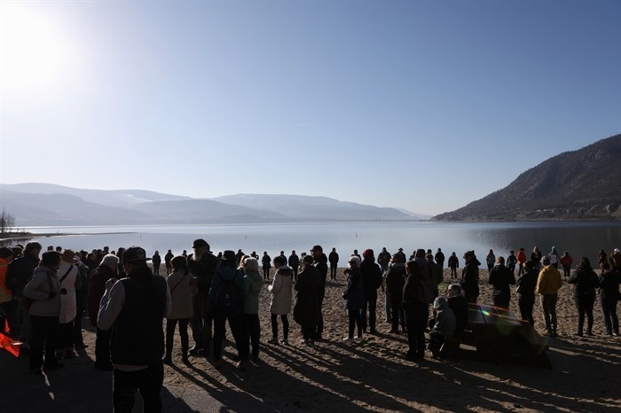 People maneuver themselves into a circle formation at the shore of cnx?lkip (Sun-Oka Beach Park) by k?úsx?nítk? (Okanagan Lake) on March 22, 2023. 