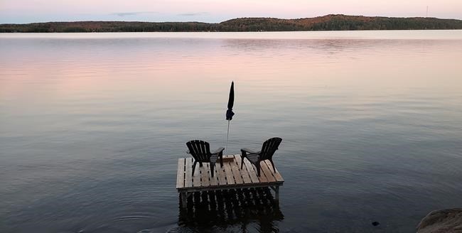 Muskoka chairs sit on a dock looking over Boshkung Lake, in Algonquin Highlands, Ont., Monday, Oct. 5, 2020. As cottage season dawns, the prospect of joint ownership with family or friends grows anew for many Canadians, budding perennially like a lakeside plant.