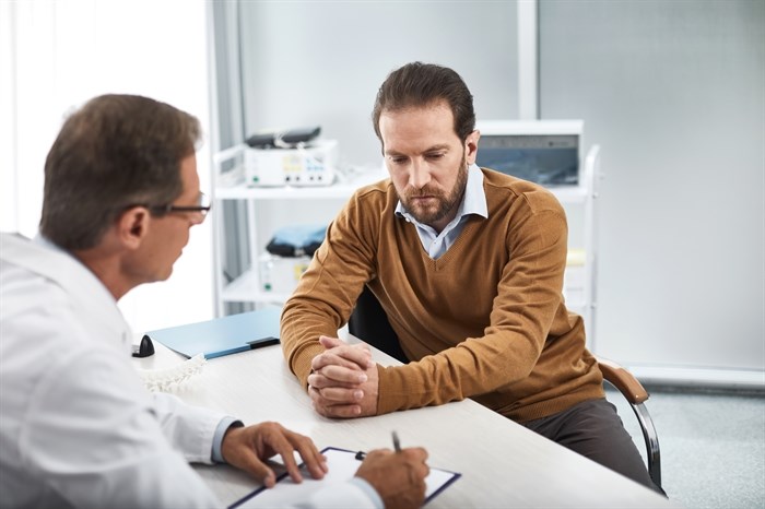 Adult doctor speaking with man