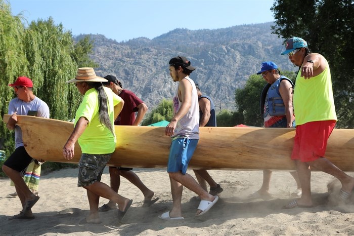 Paddlers and pullers carry a canoe to the shore of nk’mip (Osoyoos Lake) in sw?iw?s (Osoyoos) in syilx homelands, prior to the launch of the cross-border canoe journey on July 4, 2023.
