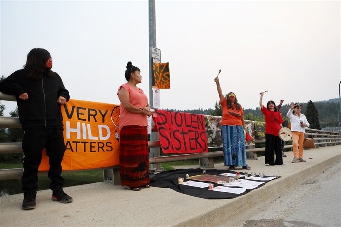 Caitlin’s family watches as drummers raise their sticks in the air during a roadblock and vigil in Enderby on the Bawtree Bridge in Secwépemc homelands on July 13, 2023.