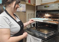 Ashley Funk pulls warm macaron shells out of the oven at her bakery in Kamloops. 