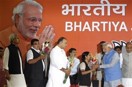 Opposition Bharatiya Janata Party (BJP) leader and India's next prime minister Narendra Modi, second right, receives flowers from party leader Sushma Swaraj, as Arun Jaitley, center, and Nitin Gadkari, second left, wait their turn, at the party headquarters in New Delhi, India, Saturday, May 17, 2014.