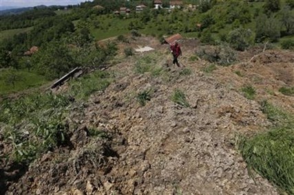 A Bosnian man walks on a broken road after a landslide which swept away eight houses near Kalesija, Bosnia, 150 kms north of Sarajevo, Sunday May 18, 2014.
