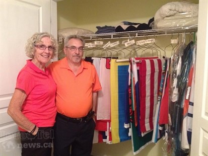 Bifano and his wife, Mavis, stand in front of the closet where all the flags are stored - neatly organized and labeled according to geographic location.