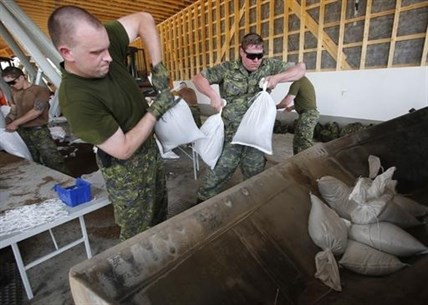 Military from Shilo work to fill and load sandbags in Portage La Prairie, Man., Saturday, July 5, 2014.
