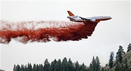 A DC-10 air tanker drops fire retardant over a wildfire Saturday, July 19, 2014, near Carlton, Wash.