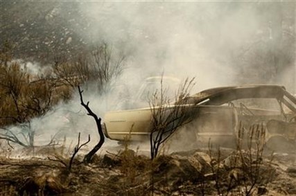 A collection of vintage cars smolder after a wildfire burnt through them on Friday, July 18, 2014, near Malott, Wash.