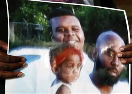 This undated family photo provided by the Brown Family and held by Michael Brown Sr., shows Michael Brown Sr., at right, his son, Michael Brown, top left, and a young child. Michael Brown, 18, was shot and killed in a confrontation with police in the St. Louis suburb of Ferguson, Mo, on Saturday, Aug. 9, 2014.