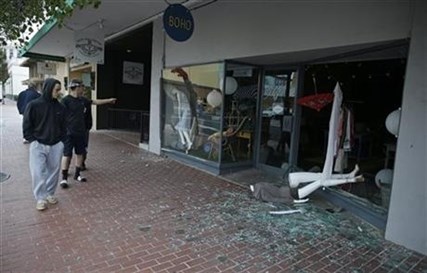 People walk past a tumbled mannequin and broken storefront window on First Street following an earthquake Sunday, Aug. 24, 2014, in Napa, Calif.