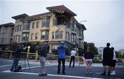 People look at a damaged building with a top corner exposed following an earthquake Sunday, Aug. 24, 2014, in Napa, Calif.