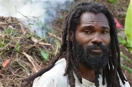 In this Sept. 2, 2014 photo, Joseph Williams, a former Jamaican soldier who is now the “scribe” for the School of Vision Rastafarian group, is shown taking a break from clearing steep farmland at the their isolated retreat in the Blue Mountains that tower over Kingston, Jamaica. 