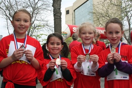 Presley, Sophie, Lizzie and Madison show off their medals after finishing the Mini Boogie portion of Boogie the Bridge Sunday morning.