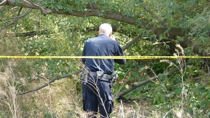 A member of the RCMP Identification Unit takes photos of the scene where a body was found this afternoon.