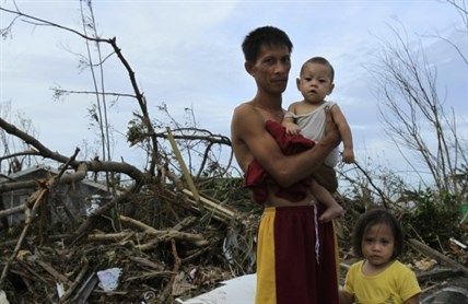 Roy Cagbian, 28, stands with his daughters, 7-month-old Shandev and 3-year-old Ashley in front of their home destroyed by Typhoon Haiyan in Tacloban, central Philippines, Monday, Nov. 11, 2013. Typhoon Haiyan, one of the strongest storms on record, slammed into six central Philippine islands on Friday leaving a wide swath of destruction and hundreds of people dead.