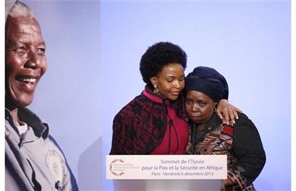 South African Minister for International Relations and Cooperation Maite Nkoana-Mashabane, left, embraces Chairperson of the African Union Commission Nkosazana Dlamini Zuma, next to the portrait of Nelson Mandela as part as the Elysee Summit for Peace and Security in Africa at the Elysee Palace, Friday, Dec.6, 2013 in Paris.