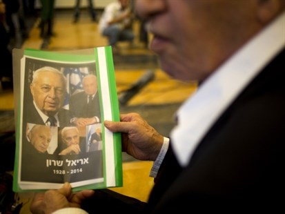 A person holds a folder with photographs of the former Prime Minister Ariel Sharon just moments after his son announced that Sharon has died in the Sheba Medical Center near Tel Aviv, Israel, Saturday, Jan. 11, 2014.