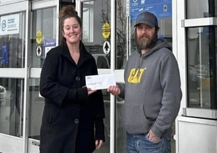 Rachel Telfer from Tolko Industries (left) hands a cheque to Kane Blake with the Okanagan Forest Task Force.